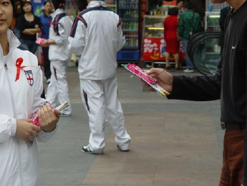 宁波新东方医院员工胸佩＂红丝带＂在街头发放安全套及预防艾滋病的宣传资料